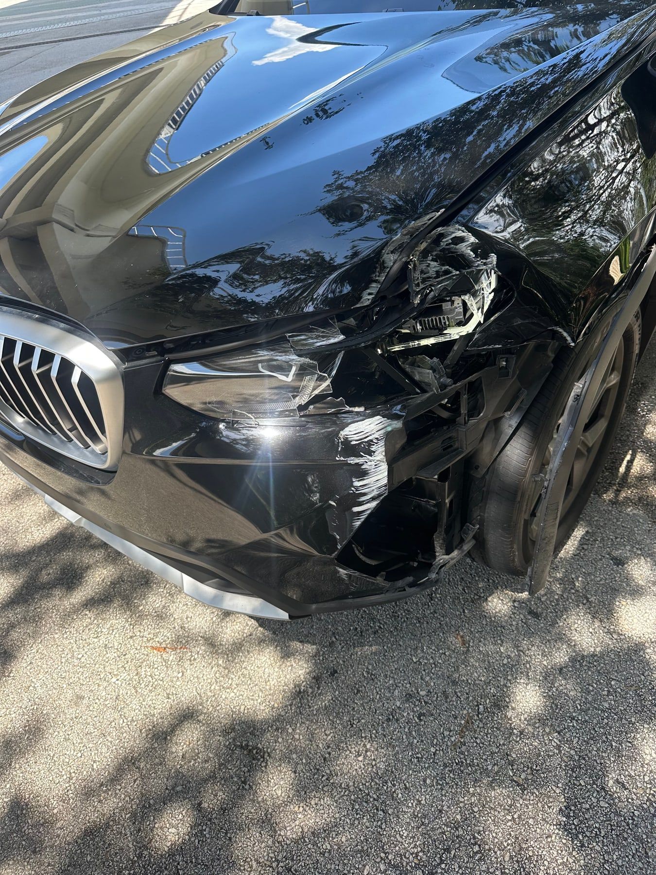 A black BMW X3 with a smashed headlight and front fender