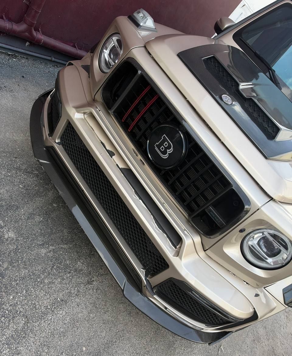 The Brabus G-wagon outside the shop, its front bumper scraped and missing paint