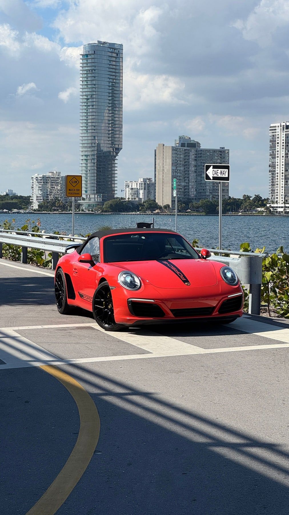 An orange Porsche 911 Carrera S cabriolet from the front, by the water